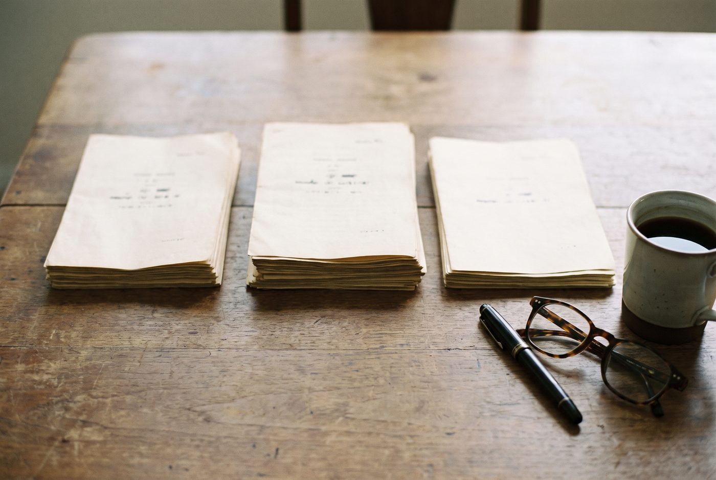 Three document sets laid side by side on a walnut table for comparison